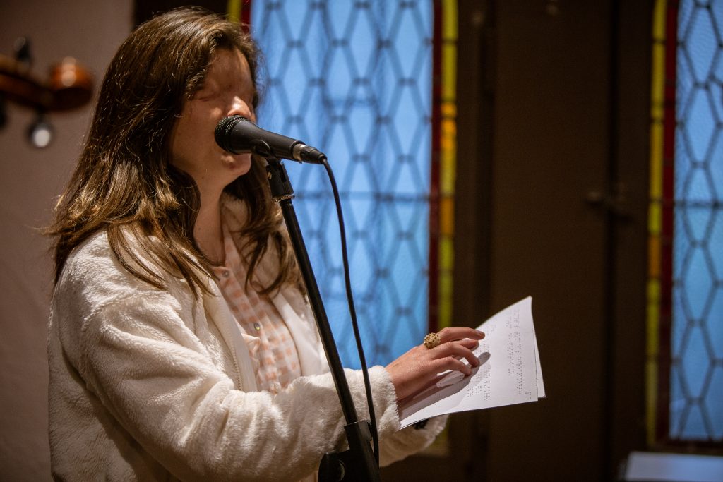 La cantante Camila Garrido con micrófono en un ensayo, leyendo su partitura en Braille